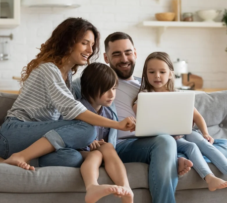 A family sitting on the couch looking at a laptop.